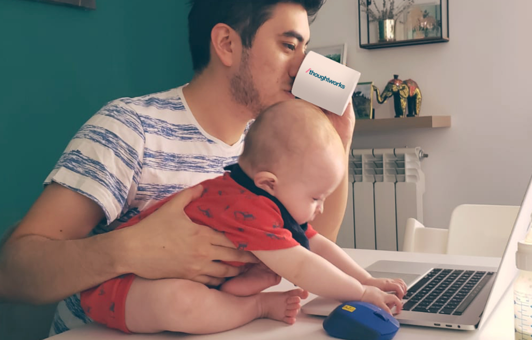 Thoughtworker with their child holding a cup and looking at the computer. Thoughtworker with their child holding a cup and looking at the computer.